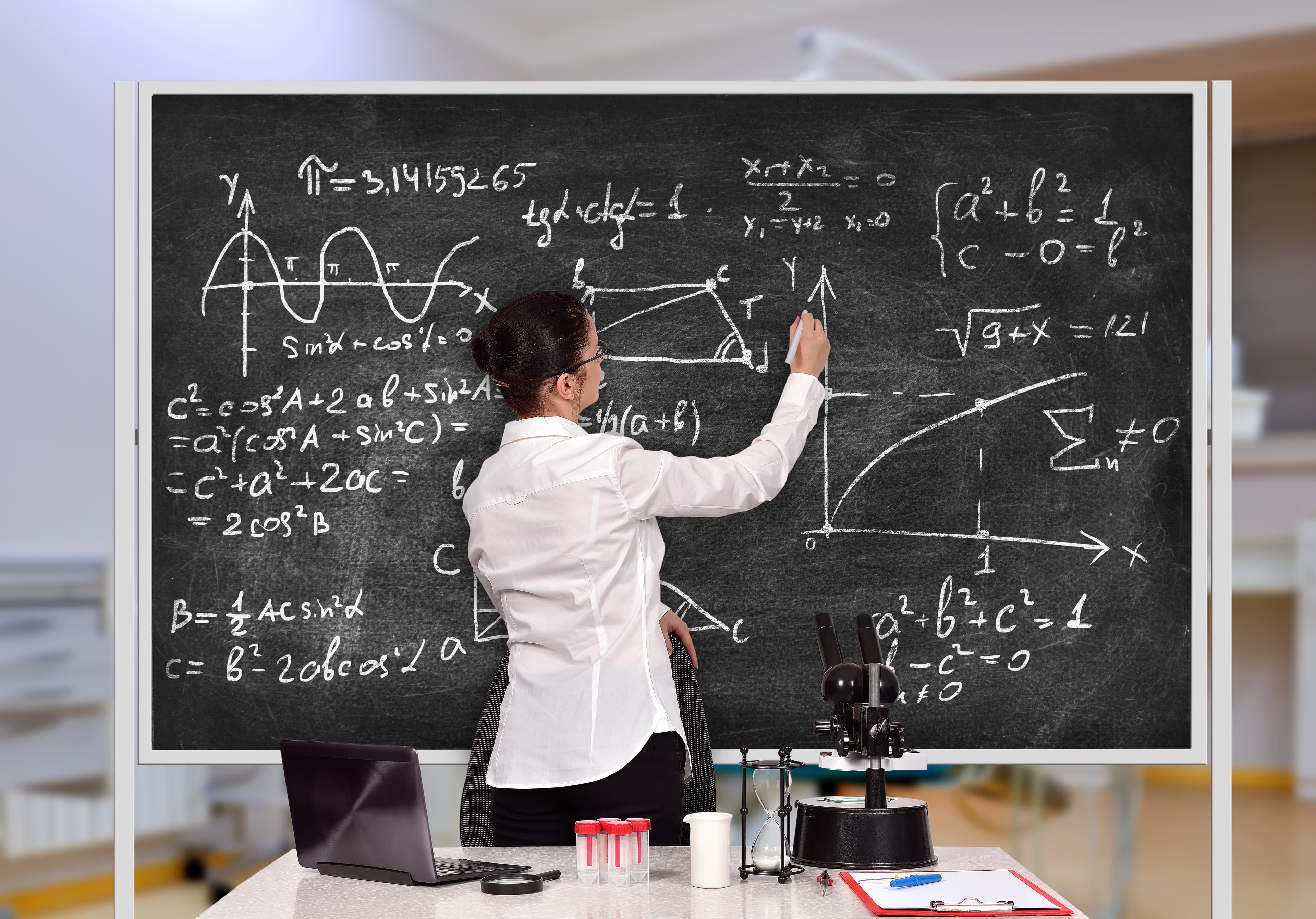 A teacher writing equations on a classroom blackboard